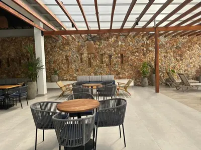 a patio with tables and chairs and a stone wall at Baia Kristal Penthouse Cartagena Playa Artificial Más Grande de Colombia in Cartagena de Indias