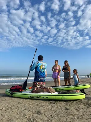 a man is holding a paddle on a beach at La Boquilla Kite House in Cartagena de Indias