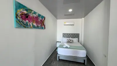 a bedroom with a bed with a painting on the wall at La Boquilla Kite House in Cartagena de Indias