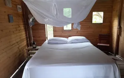 a bedroom with a white bed in a wooden room at CARDUMEN ARTE y COCINA in Cartagena de Indias