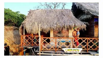 two people standing outside of a thatch hut at CARDUMEN ARTE y COCINA in Cartagena de Indias
