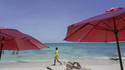 a person walking on a beach with two red umbrellas at Beautiful Cabaña facing the Caribbean Sea! in Cartagena de Indias