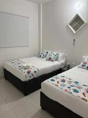 two beds in a room with white walls at Casa Turbay in Cartagena de Indias