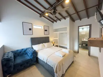a bedroom with a bed and a blue chair at Casa Martina Manga Cartagena in Cartagena de Indias