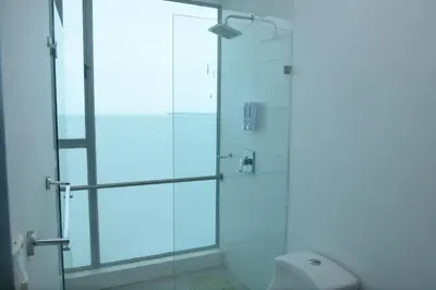 a glass shower stall with a toilet in a bathroom at Moderno 3 Alcobas Frente a Playa in Cartagena de Indias