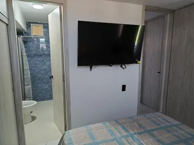 a bedroom with a flat screen tv on the wall at Búho, alameda del río in Barranquilla