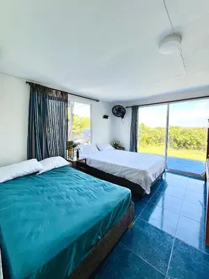 a bedroom with two beds and a large window at Hermosa Cabaña privada cerca a la Playa in Puerto Colombia