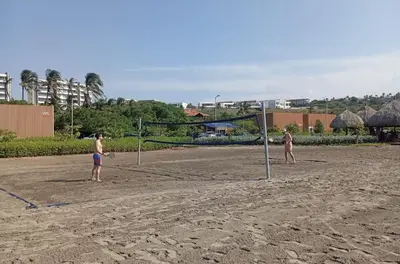 two people playing a game of volleyball on the beach at Hermosa Cabaña privada cerca a la Playa in Puerto Colombia