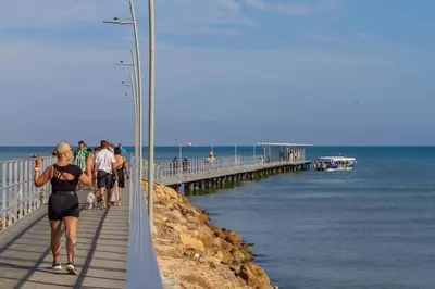 a group of people walking on a pier next to the ocean at La Morada Apartamento in Coveñas
