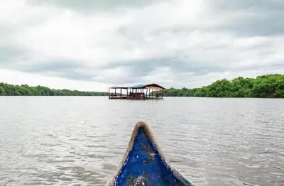 a boat in the water with a house in the background at La Morada Apartamento in Coveñas