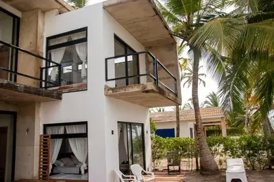 a white house with a balcony and a palm tree at Taipan Casa de Playa in El Puertón