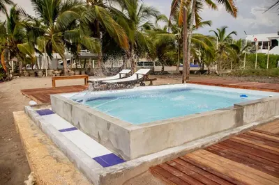 a large stone pool with chairs and palm trees at Taipan Casa de Playa in El Puertón