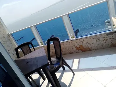 a table and chairs on a balcony with a view of the ocean at Bahia del caribe Apartment in Cartagena de Indias