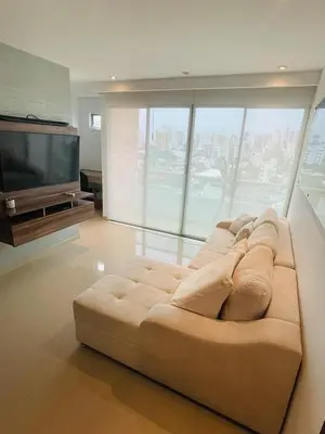 a large couch in a living room with a television at aptobibibarranquilla in Barranquilla