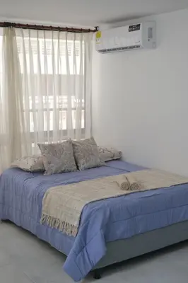 a bed with a blue blanket and a window at Bocagrande cerca del mar in Cartagena de Indias