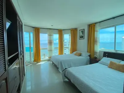 a hotel room with two beds and a large window at Tropical Paradise - vista al mar, el Laguito Cartagena in Cartagena de Indias