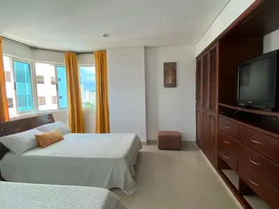 a bedroom with two beds and a flat screen tv at Tropical Paradise - vista al mar, el Laguito Cartagena in Cartagena de Indias