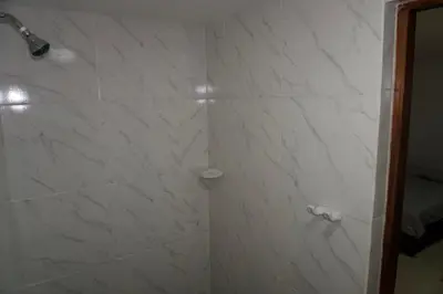 a bathroom with a shower with white marble walls at Hostal Barrio Abajo in Barranquilla