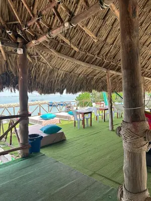 a straw hut with tables and chairs on the beach at Hotel Restaurante Arrecife in Isla de Tierra Bomba