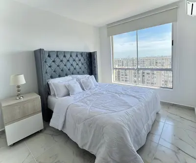 a white bedroom with a bed and a large window at Apartamento en el Norte de Barranquilla in Barranquilla