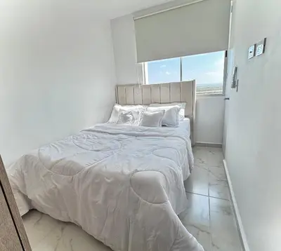 a white bed in a white bedroom with a window at Apartamento en el Norte de Barranquilla in Barranquilla