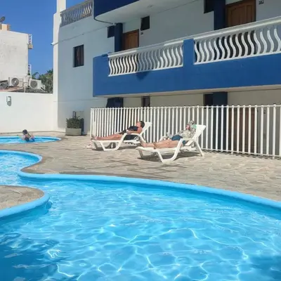 two people sitting in lawn chairs next to a swimming pool at Apartamento en Bello Horizonte, Santa Marta in Santa Marta