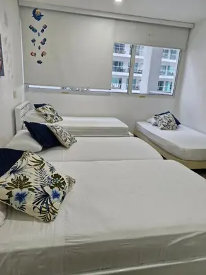 a room with three beds with pillows and a window at Apartamento con vista al Mar Cartagena Morros 3 in Cartagena de Indias