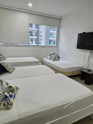 a room with three beds and a flat screen tv at Apartamento con vista al Mar Cartagena Morros 3 in Cartagena de Indias