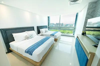 two beds in a room with a large window at Apartment Hilton Garden Inn Building in Barranquilla