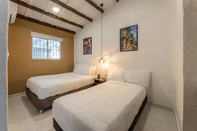 two beds in a room with white walls at Amplio apartamento familiar de 2 habitaciones dentro de la Ciudad Amurallada - AC, Wifi rapido y Agua caliente in Cartagena de Indias