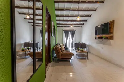 a waiting room with chairs and a television and green walls at Amplio apartamento familiar de 2 habitaciones dentro de la Ciudad Amurallada - AC, Wifi rapido y Agua caliente in Cartagena de Indias