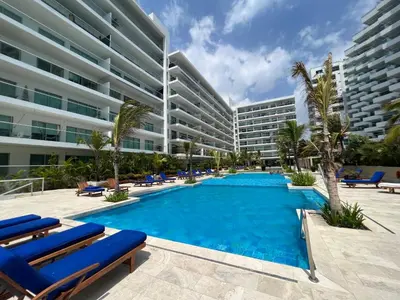 a swimming pool with blue lounge chairs and a large building at Espectacular apto frente al Mar! in Cartagena de Indias