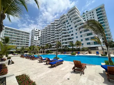 a resort with a pool and chairs and a large building at Espectacular apto frente al Mar! in Cartagena de Indias
