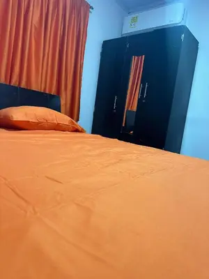 a bed with an orange comforter and a black cabinet at Apartamento #1 in Puerto Colombia