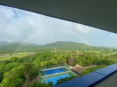 a rainbow in the sky over a house with a swimming pool at Playa Los alcatraces in Santa Marta