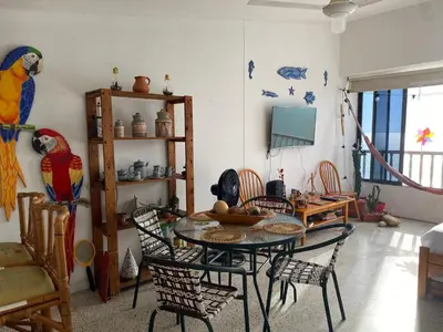 a dining room with a table with chairs and parrots on the wall at Playa Los alcatraces in Santa Marta