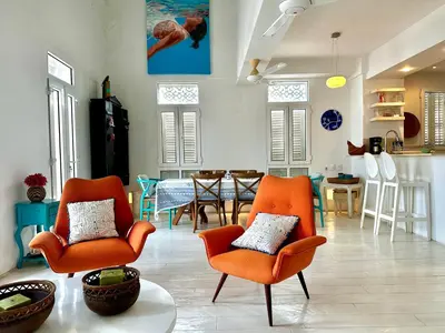 a living room with two orange chairs and a table at by Calamari Homes - El Porvenir 401 walled city in Cartagena de Indias