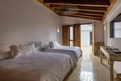 a bedroom with two beds and a table and a mirror at Colonial House with Pool in Cartagena de Indias
