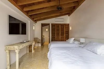 two beds in a room with a desk and a table at Colonial House with Pool in Cartagena de Indias