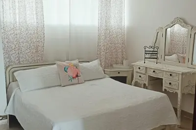 a white bedroom with a bed and a dressing table at Edificio Mares de Coveñas apto frente al Mares de coveñas in Coveñas