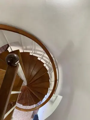 a spiral staircase in a building with a wooden railing at Acogedor Apartamento cerca al Mar in Cartagena de Indias