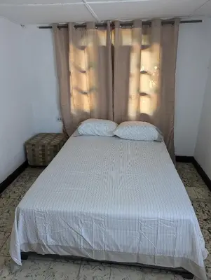 a bed with white sheets and pillows in a room at BAQ central point in Barranquilla