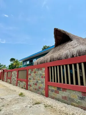a building with a thatch roof and a red fence at Cabaña La Roca in San Antero