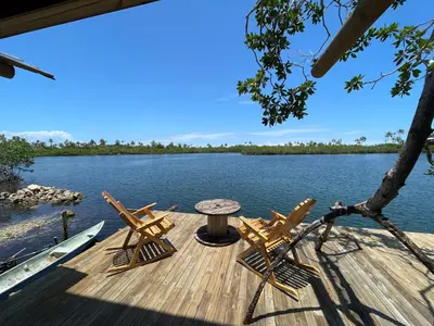 a wooden deck with chairs and a table on the water at Prueba1 in Tintipan Island