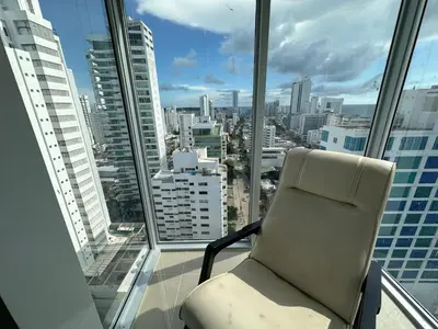 a chair in a room with a view of a city at Apartamento Magnoloft Bocagrande in Cartagena de Indias