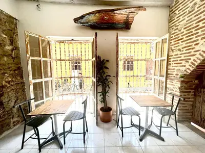 two tables and chairs in a room with windows at Pachamama Hostel in Cartagena de Indias