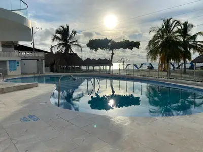 a large swimming pool with palm trees in the background at Espectacular apto frente al mar in Coveñas