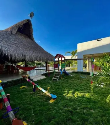 a playground in a resort with a straw umbrella at Villa Maty Casa Campestre in Turbaco