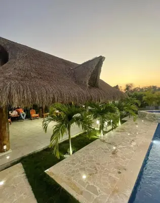 a resort with a straw roof and a swimming pool at Villa Maty Casa Campestre in Turbaco