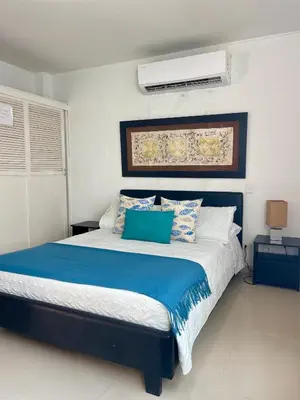 a bedroom with a large bed with blue and white pillows at Apartamentos cerca al hotel Las Americas in Cartagena de Indias